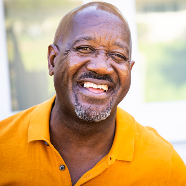 older man in orange polo smiling
