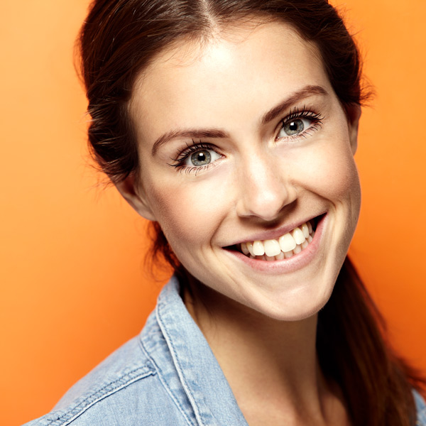 young woman with orange background smiling